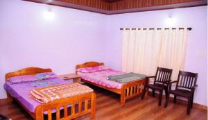 two beds in a room with two chairs and a table at Simply Coorg Estate Villa in Virajpet
