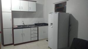 a kitchen with white cabinets and a refrigerator at Chale Verde in Gramado