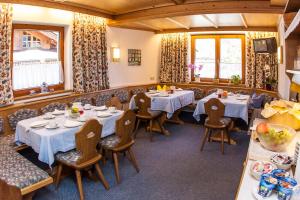 a dining room with tables and chairs and windows at Frühstückspension & Ferienhaus Fädnerspitze in Galtür