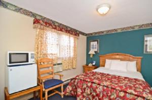 Habitación de hotel con cama y silla en Americas Best Value Inn - Stonington, en Stonington
