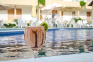 a drink with a lime in a glass next to a pool at Porto da Serra Hotel in Gravatá