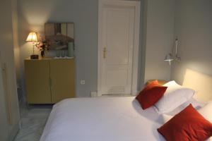 a bedroom with a large white bed with red pillows at Luxurious 2 bedroom flat in a historic building in Seville