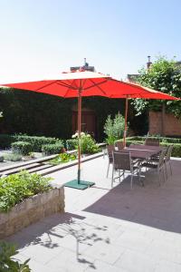 une table et des chaises sous un parapluie rouge dans l'établissement B&B De Gilleminus, à Tamise
