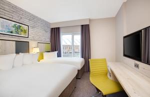 a hotel room with two beds and a flat screen tv at Leonardo Hotel Manchester Central - Formerly Jurys Inn in Manchester