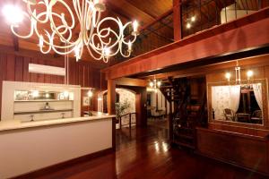 um quarto amplo com pisos em madeira e um lustre em Pousada do Verde Gramado em Gramado