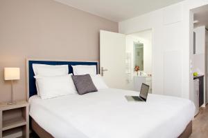 1 dormitorio con cama blanca y ordenador portátil en Sejours & Affaires Paris-Davout, en París