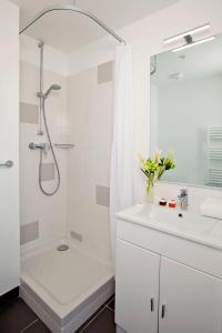 a white bathroom with a shower and a sink at Sejours & Affaires Paris-Davout in Paris