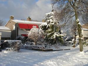a snow covered tree in front of a house at Bed and Breakfast Oosterpark in Harlingen