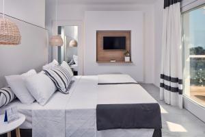 - une chambre blanche avec un grand lit et une fenêtre dans l'établissement Archipelagos Hotel - Small Luxury Hotels of the World, à Kalo Livadi