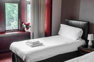 格拉斯哥的住宿－富勒頓公園酒店，一间卧室配有一张带白色床单的床和一扇窗户。