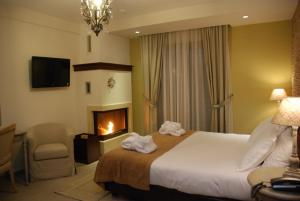 a hotel room with a bed and a fireplace at Agapi Luxury Hotel in Kato Loutraki