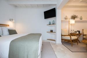 Dormitorio con cama, escritorio y TV en S'Hotelet d'es Born - Suites & SPA, en Ciutadella