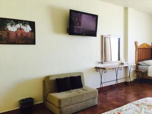 ein Wohnzimmer mit einem Sessel und einem Fernseher an der Wand in der Unterkunft Hotel Mariazel in Bernal