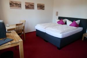 1 dormitorio con cama con almohadas rosas y escritorio en Hotel Garni Brauhof Niederwiesa en Niederwiesa