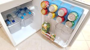 an open refrigerator filled with cans and bottles of water at Hotel Premier in Campo Grande