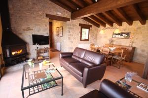 a living room with a leather couch and a fireplace at El Mirador del Bosqueró in Les Planes d'Hostoles
