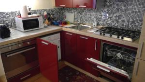 a kitchen with red cabinets and a stove and a microwave at La Dimora di Nadine in La Spezia +10 photos