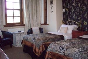 a hotel room with two beds and a chair at Lairg Highland Hotel in Lairg