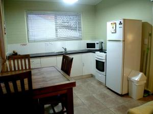 a kitchen with a refrigerator, stove, microwave and a table at Coconut Palms On The Bay in Hervey Bay
