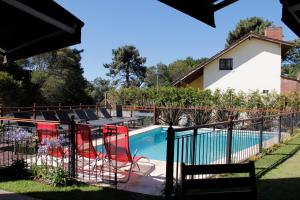 オステンデにあるAyres del Esteの赤い椅子とフェンス付きのスイミングプール