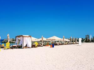 a beach with chairs and tables and umbrellas on it at Apartments For You in Olimp