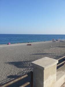 a bench on a beach with the ocean in the background at appartamento Claudia in Roccalumera