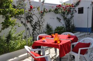 a red table with white chairs and a red table cloth at Apartamentos Campos 1 in Porto Covo