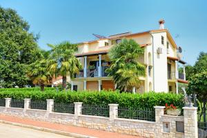 a house with palm trees in front of a fence at Apartments Pilic in Rošini