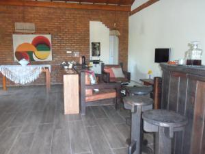 a room with tables and stools and a brick wall at Cais Dourado Pousada in Barra Grande