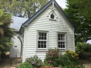 a white house with flowers in the front yard at The Old School House in Te Awamutu