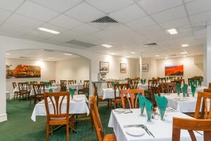 un comedor con mesas blancas y sillas de madera en Flag Motor Lodge, en Perth