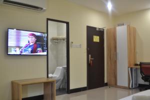 baño con TV en la pared y aseo en My Inn Hotel Kota Samarahan, en Kota Samarahan