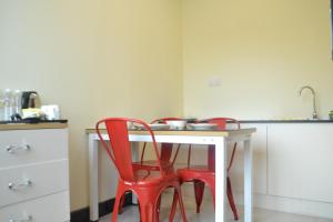 a kitchen with two red chairs at a white table at My Inn Hotel Kota Samarahan in Kota Samarahan