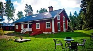 a red house with a table and chairs in front of it at STF Kungsgården Långvind in Enånger