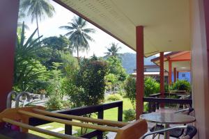 einen Balkon mit Tischen und Stühlen und Gartenblick in der Unterkunft Baan Longhaad in Ko Lanta