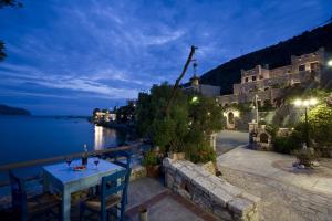 a table and chairs on a patio near the water at night at Elixirion Guest House in Karavostasi