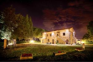 una gran casa de piedra por la noche con luces en Agriturismo L'Antica Quercia, en Pomarance