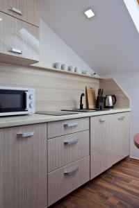 cocina con armarios de madera y microondas en Apartament City Center Sky, en Krynica-Zdrój