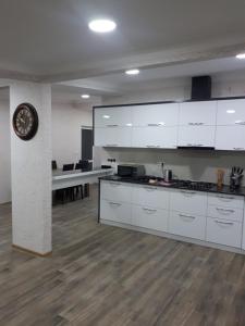 a kitchen with white cabinets and a clock on a wall at The ideal penthouse in Tbilisi City