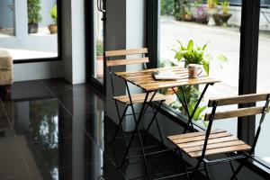 a wooden table and two chairs in front of a window at Twentynine KV Apartel in Nonthaburi