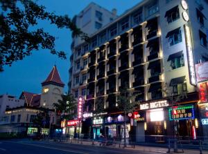 uma rua da cidade com um edifício e uma torre do relógio em MG Hotel (青岛民国酒店) em Qingdao