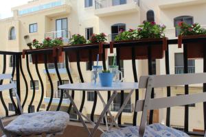 a table and chairs on a balcony with flowers at South Pacific Flat 2 in Marsaskala