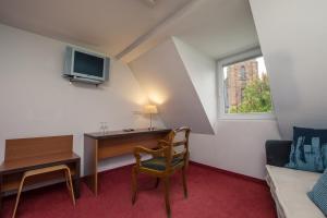 Habitación pequeña con escritorio y ventana. en Hôtel Restaurant Notre Dame, en Haguenau
