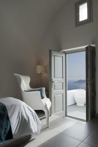 a bedroom with a mirror and a bed and a chair at Regina Mare-Adults Only Hotel in Imerovigli