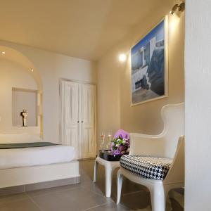 a bedroom with a bed and a table with flowers at Regina Mare-Adults Only Hotel in Imerovigli