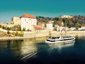a boat traveling down a river near a city at Boutique Hotel Morgentau in Passau