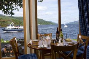 - une table avec des verres à vin et un bateau dans l'eau dans l'établissement Lovat Loch Ness Apartment with private roof terrace, à Fort Augustus