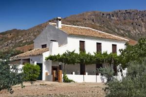 una casa bianca con una montagna sullo sfondo di Cortijo el llano Priego de Córdoba a Las Lagunillas