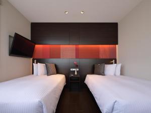 two beds sitting next to each other in a room at Red Roof Inn & Suites Osaka Namba Nipponbashi in Osaka