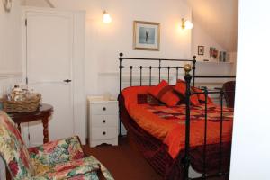 a bedroom with a bed with red pillows and a chair at Baytree in Minehead
